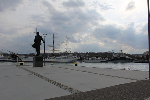 Gdynia, Port, Poland. Monument to Tadeusz Wenda, in the background a school sailing ship, museum, Dar Pomorza.