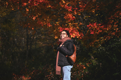 Brazilian woman in front of colorful autumn trees.