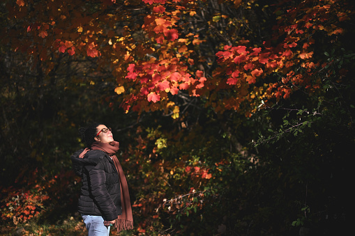 Portrait of a multiracial woman enjoying the autumn color leafs in nature.