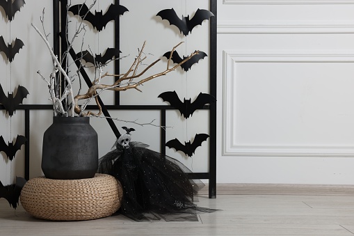 Paper bats and festive decor near white wall, space for text. Halloween celebration