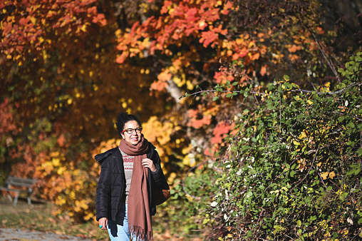 Portrait of a latin woman walking in autumn city park.
