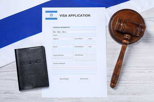 Immigration to Israel. Visa application form, gavel, passport and flag on white wooden table, flat lay