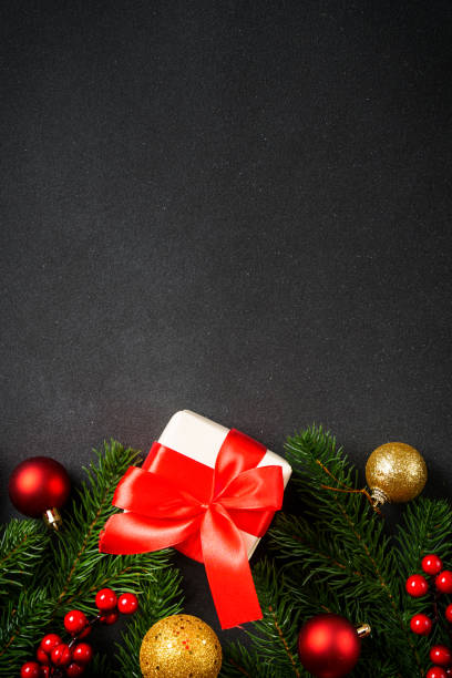 istock Christmas background with christmas tree, present box and holidays decorations at black. 1840694533