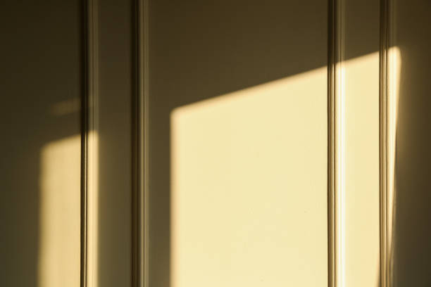 istock Light and shadow from window on beige wall indoors 1840695835