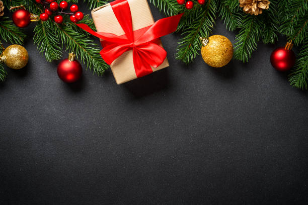 istock Christmas background with christmas tree, present box and holidays decorations at black. 1840697128