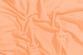 Crumpled fabric of a peach color as a background