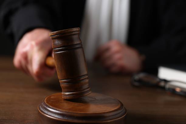 istock Judge with gavel sitting at wooden table, closeup 1840748140