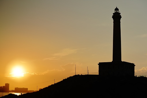 Landscape photography at sunset of the Cabo de Palos lighthouse in which you can see its silhouette against the light, Murcia, Spain