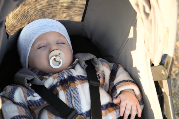 Cute little child with pacifier sleeping in stroller outdoors