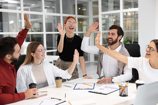 Team of employees joining hands in office