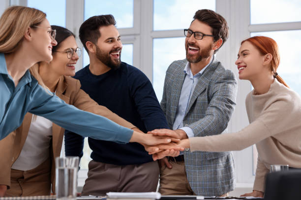 istock Team of employees joining hands in office 1840810603