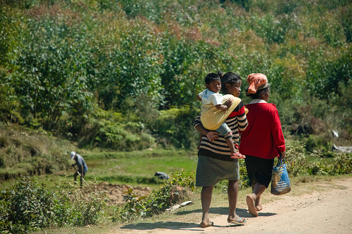 Madagascar. 25 oktober 2023.Typical Madagascar landscape . people in bright clothes walking along road. Women with heavy burden on their heads, baskets and bags