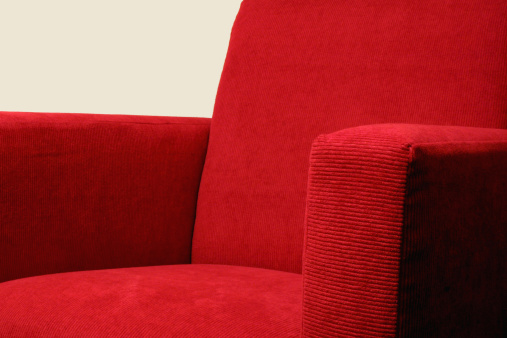 detail of a modern red corduroy armchair (please note that the focus is on the front arm-rest)