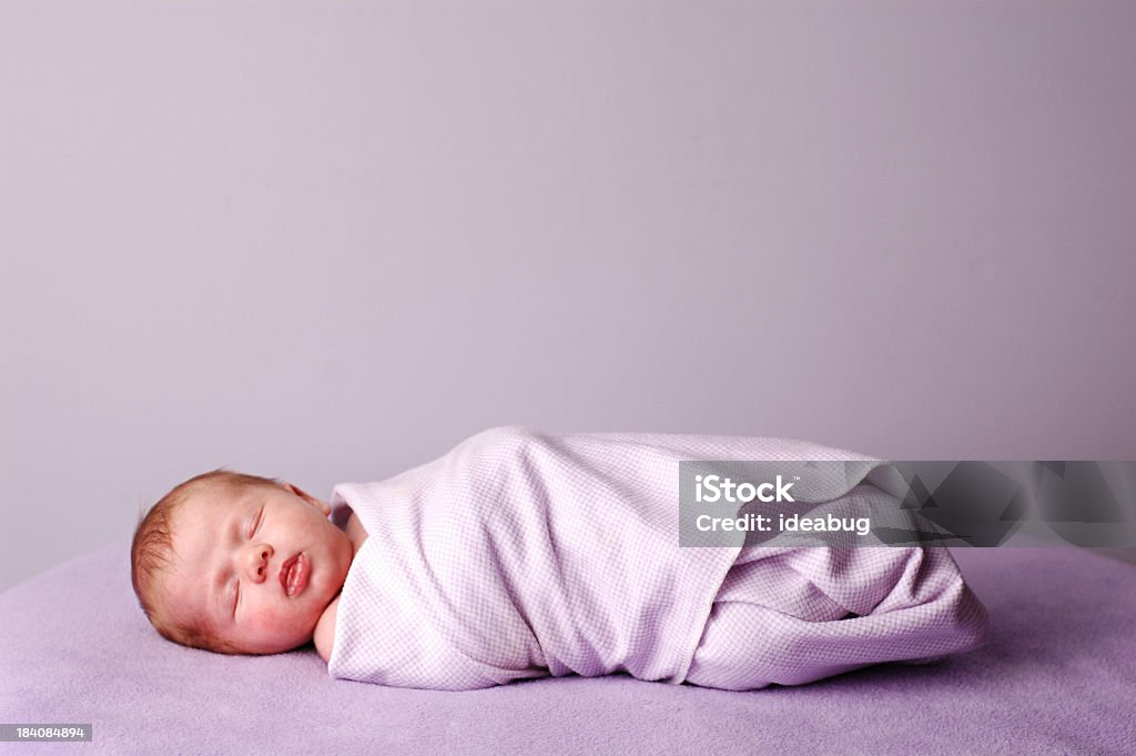 Sleeping, Swaddled Newborn Color photo of a beautiful little newborn baby swaddled and sleeping on a soft, purple blanket.  Room for text above. Baby - Human Age Stock Photo