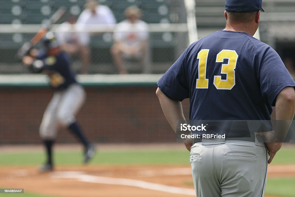 Coaching a man looking on as a batter hits Baseball - Ball Stock Photo
