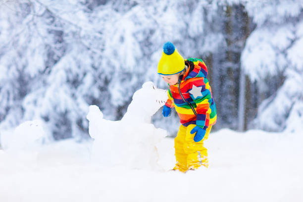 istock Child making snowman. Kids play in snow in winter 1840859619