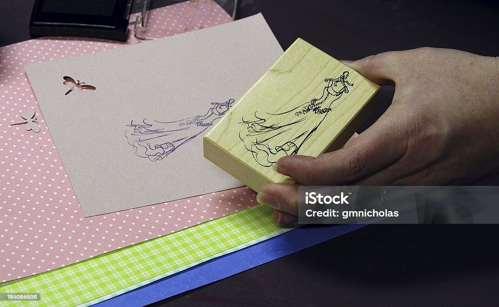 Hand stamping a womans hand holding a stamp.  Paper in the background shows stamp and a cut out Rubber Stamp Stock Photo