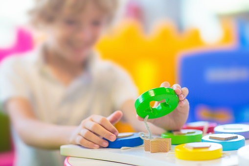 Little boy in kindergarten or daycare. Child playing with colorful educational toys in preschool. Kids play in indoor playground. Early education and child care. Student in primary school class.