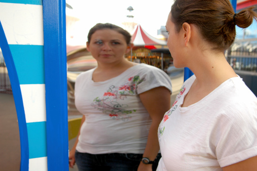 A woman examines herself in front of a funhouse mirror.  Here is a link to my other