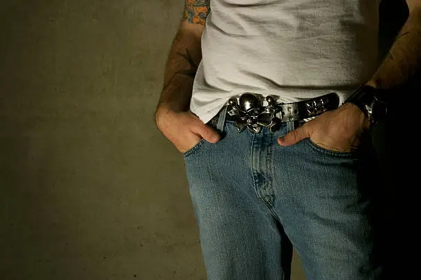 Young male sporting tattoos and skull belt buckle