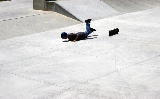 Young boy falling off of skateboard at skate parkSimilar: