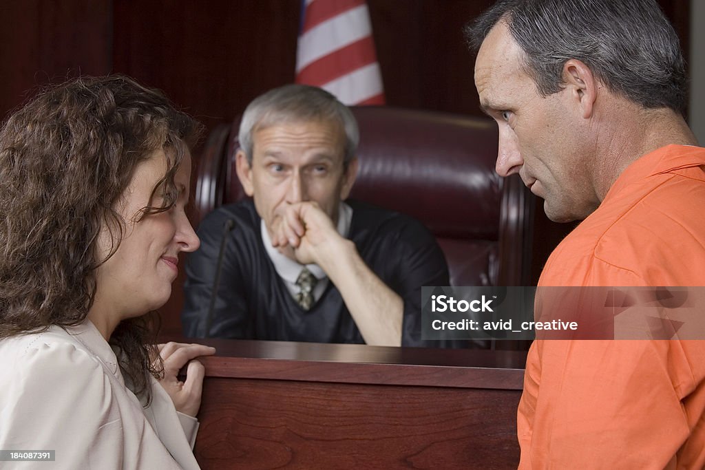 US Judicial System-judge watching A criminal and his female attorney (or wife) with a male judge in the background. Selective focus on foreground. Bench Stock Photo