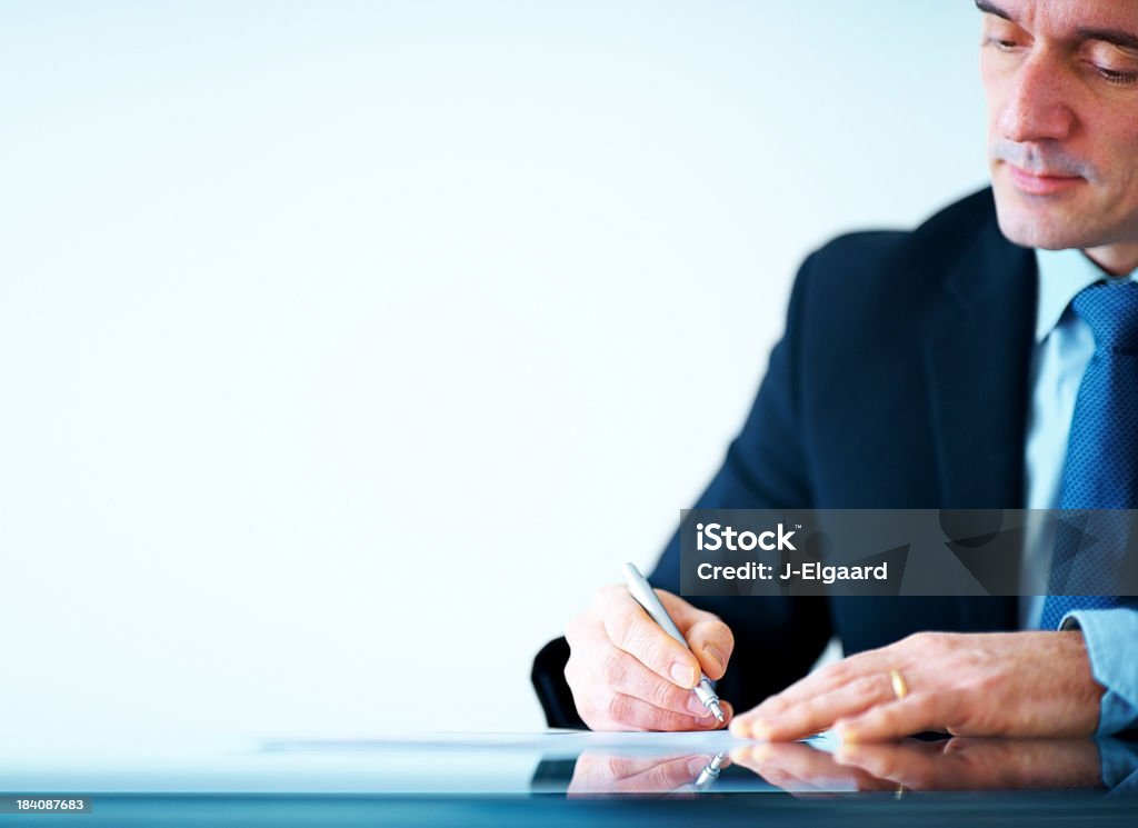 executive business maturo scrivendo su Carta al banco di ufficio - Foto stock royalty-free di Contratto