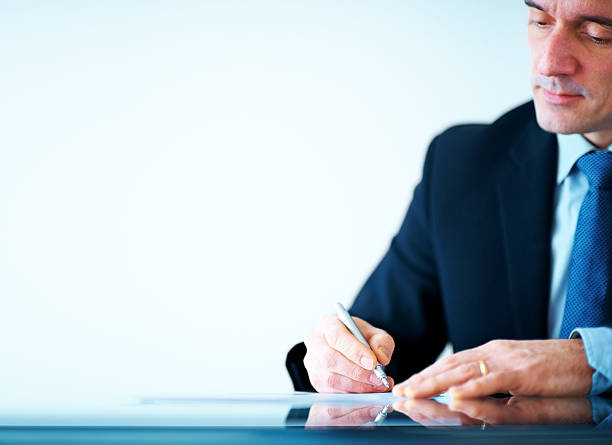 istock Mature business executive writing on papers at office desk 184087683