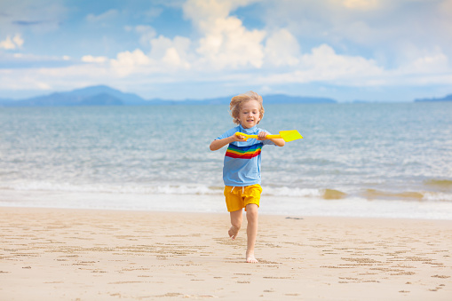 Child playing on tropical beach. Little boy with bucket and spade at sea shore. Family summer vacation. Kid building sandcastle. Water and sand fun for children. Kids play, build castle on ocean coast