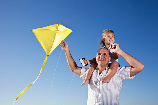 Father, 30s, and daughter, 2 years, flying a kite