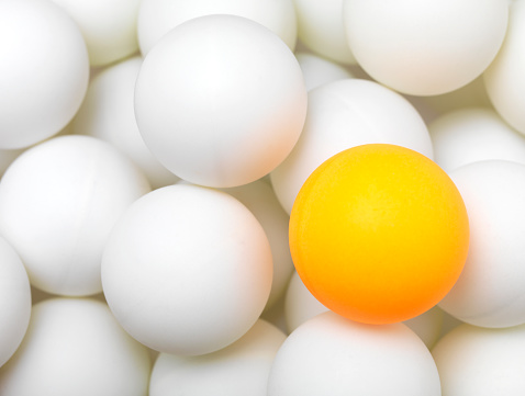 group of white balls with single orange ball