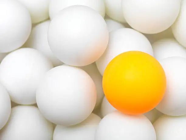 group of white balls with single orange ball