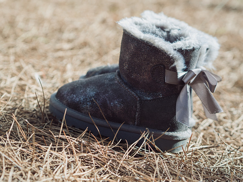 In this photo, children's soft grey sheepskin boots stand on the earthy backdrop of a Sardinian winter forest floor. The lush texture of the pine needles complements the cozy allure of the boots, creating a serene image that encapsulates the essence of a winter day in Sardinia. The neutral tones harmonize, offering a visual tapestry of natural comfort in the midst of the tranquil winter landscape.