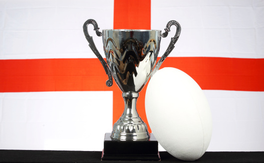 A trophy and rugby ball in front of an England flag