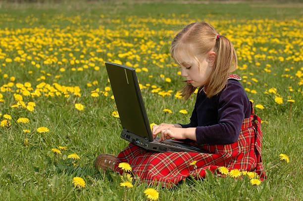 rapariga no prado com computador portátil - child office chaos computer monitor imagens e fotografias de stock