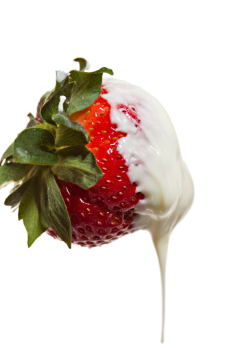 Close up of a  luscious ripe red strawberry  dripping after having been dunked in some molten white chocolate.