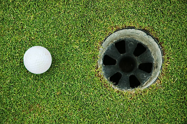 istock Golf ball on green grass near hole 184093588