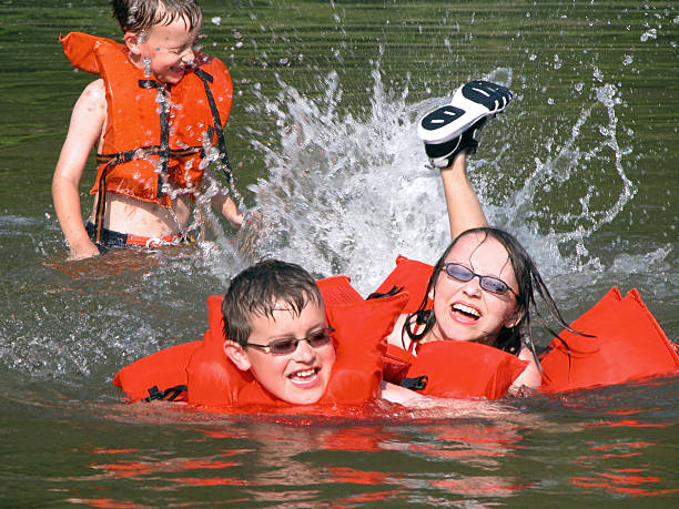Three Young Children Playing and Swimming with Life Vests