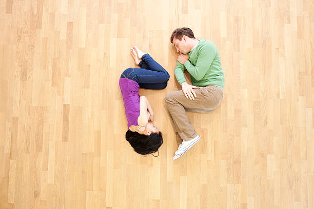 Sleeping couple A young couple, lying on a wooden floor, eyes shut. hugging knees stock pictures, royalty-free photos & images