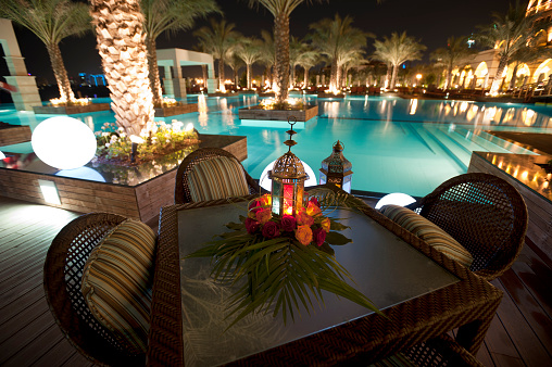 Tourist resort pool at night with table and chairs in Dubai UAE