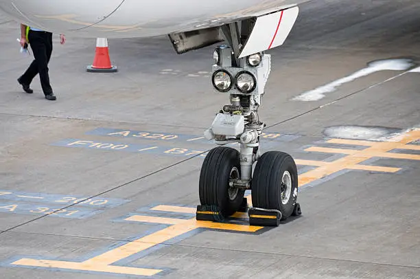 Close-up of a commercial airliners nosewheel chocked on the apron of an airport