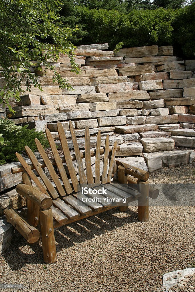 Befestigte Flächen Gartenanlage mit rustikalen Log Bank, Rock, Stone Wall - Lizenzfrei Blumenbeet Stock-Foto