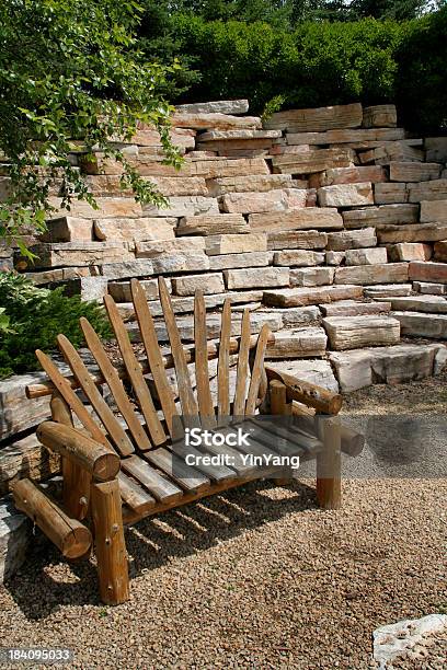 Befestigte Flächen Gartenanlage Mit Rustikalen Log Bank Rock Stone Wall Stockfoto und mehr Bilder von Blumenbeet