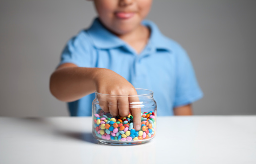 Little boy licking his lips while taking candy from the candy jar.