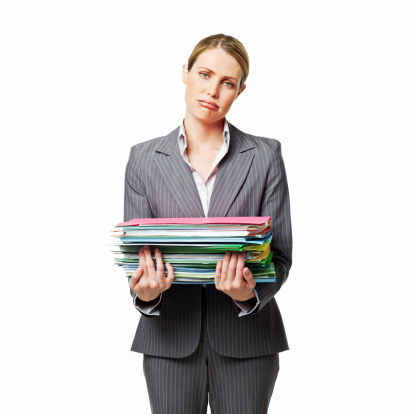 Businesswoman with a large stack of work frowns at the camera. Square shot. Isolated on white.