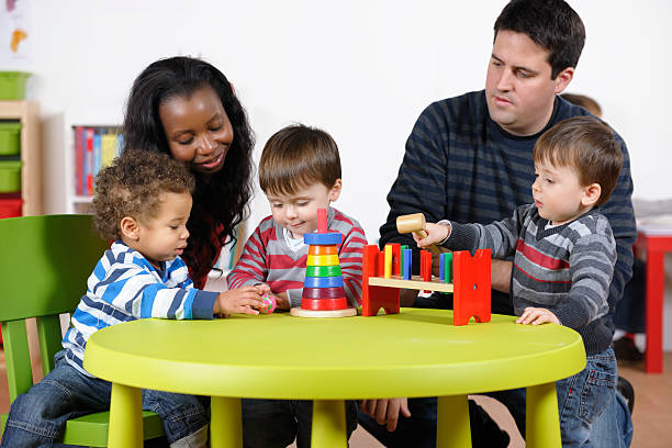 istock Carers Supervising Group Of Toddlers Using Developmental Toy At Playtime 184096421