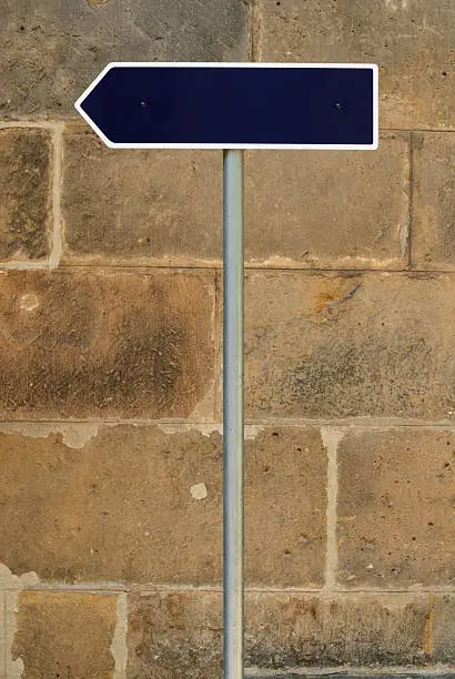 Guidepost in front of a sandstone wall