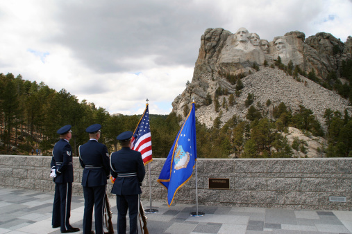 Air Force officers in full dress admire patriotic scene of Mount Rushmore.