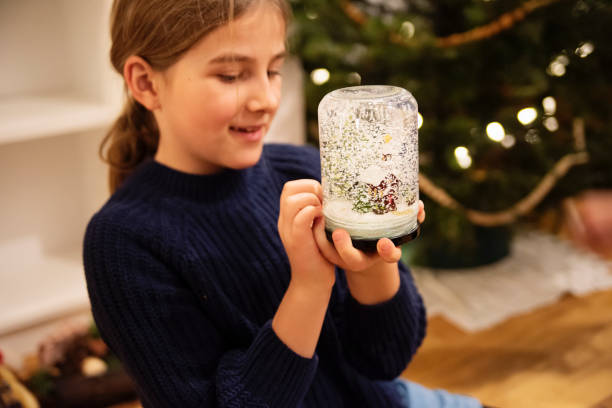 Young girl playing with a snow globe decoration at home.