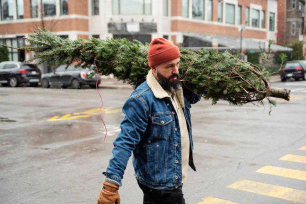 istock Urban millennial man bringing home a Christmas tree. 1840968904